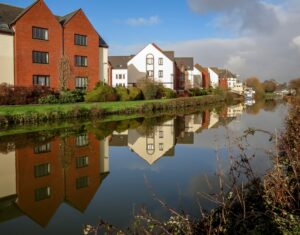 brown and white concrete buildings beside body of water under blue sky during daytime