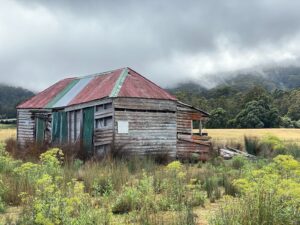 brown wooden house on green grass field under cloudy sky during daytime