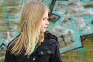 woman in black jacket standing near green wall