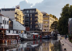 Serene view of London's canal with modern architecture reflecting in calm waters at dusk.