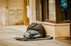 man in gray hoodie lying on gray concrete floor during daytime