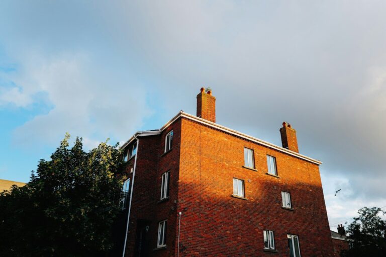 Brick building with chimneys against a cloudy sky.