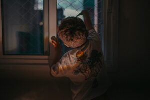 Young boy looking out a window at night